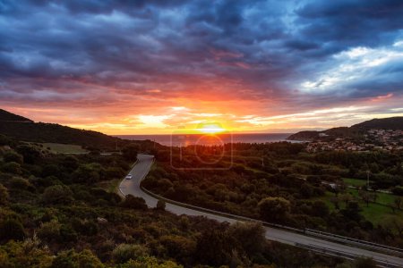 Foto de Scenic Highway on the Sea Coast near Small Town, Solanas, Sardinia. Dramatic Sunset Sky. - Imagen libre de derechos