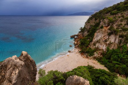 Téléchargez les photos : Sandy Beach on a rocky coast near Cala Gonone, Sardinia. Cloudy Sunrise Sky. - en image libre de droit
