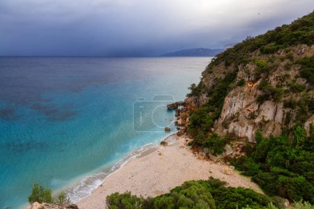 Foto de Sandy Beach on a rocky coast near Cala Gonone, Sardinia. Cloudy Sunrise Sky. - Imagen libre de derechos
