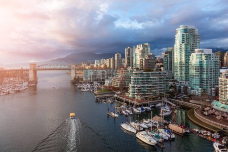 Aerial View of Granville Island in False Creek with modern city skyline and mountains in background. Downtown Vancouver, British Columbia, Canada. Sunset Sky