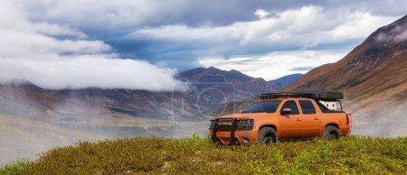 Camion hors route 4x4 dans les prairies avec paysage de montagne. Composition du véhicule de rendu 3d. Image de fond du Yukon, Canada.