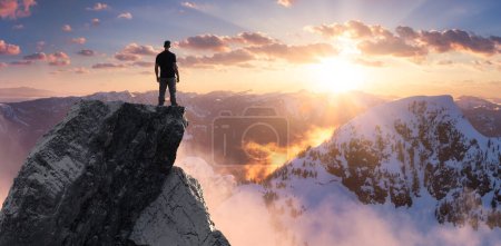 Adventurous Man Hiker standing on top of icy peak with rocky mountains in background. Adventure Composite. 3d Rendering rocks. Aerial Image of landscape from BC, Canada. Sunset Sky. 3D Illustration