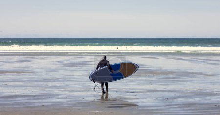 Téléchargez les photos : Surfeur Marcher vers l'océan pour surfer Vagues. West Coast of Vancouver Island in Tofino, BC, Canada. Voyage aventure - en image libre de droit