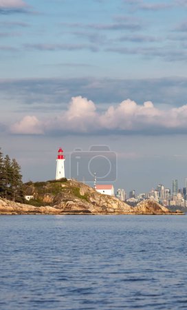 Téléchargez les photos : Parc phare sur Rocky Shore avec le centre-ville en arrière-plan. West Vancouver, Colombie-Britannique, Canada. Coucher de soleil ensoleillé et nuageux - en image libre de droit