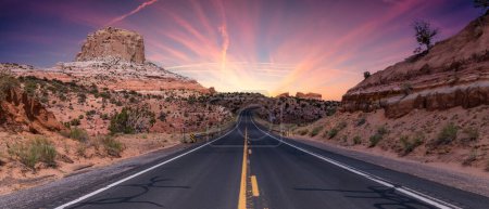 Foto de Scenic Road in the Dry Desert with Red Rocky Mountains in Background (en inglés). Twillight Sky Art Render. Near Page, Arizona, Estados Unidos de América. Viaje de aventura. - Imagen libre de derechos
