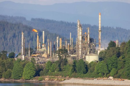 Photo for Oil Refinery Plant in Port Moody, Vancouver, BC, Canada. Sunny day. Mountains in background. - Royalty Free Image