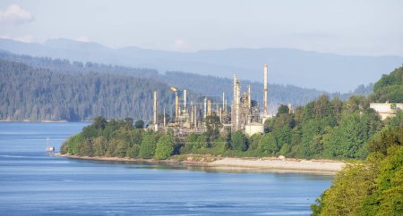 Téléchargez les photos : Usine de raffinage de pétrole à Port Moody, Vancouver, BC, Canada. Journée ensoleillée. Montagnes en arrière-plan. - en image libre de droit