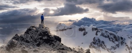 Foto de Hombre aventurero de pie en la cima del acantilado de la montaña. Compuesto de Aventura Extrema. 3d Rendering Peak. Imagen aérea de fondo de British Columbia, Canadá. - Imagen libre de derechos