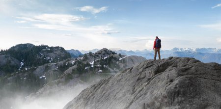 Photo for Adventurous Man Standing on top of Mountain Cliff. Extreme Adventure Composite. 3d Rendering Peak. Background Aerial Image from British Columbia, Canada. - Royalty Free Image