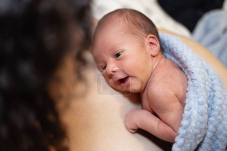 Foto de Adorable bebé recién nacido sentado en el pecho de la madre. Piel a piel. Mirando - Imagen libre de derechos