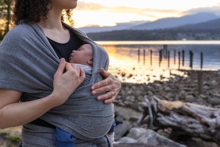 Photo for Small newborn baby boy with his mother at a park. Sunset. Barnet Marine Park, Burnaby, Vancouver, BC, Canada. - Royalty Free Image