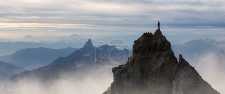 Téléchargez les photos : Epic Adventure Composite of Man Randonneur au sommet d'une montagne rocheuse. Coucher de soleil spectaculaire. 3d Crête de rendu. Paysage de fond d'Amérique du Nord. Concept de liberté. - en image libre de droit