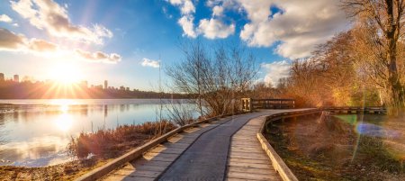 Photo for Wooden pathway in a city park by the lake. Sunset. Deer Lake, Burnaby, Vancouver, BC, Canada. - Royalty Free Image