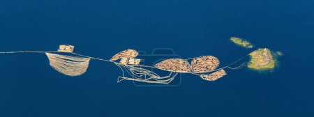 Téléchargez les photos : Vue aérienne du bois de sciage dans la mer attaché à une île rocheuse. Pris à Port Alberni, île de Vancouver, Colombie-Britannique, Canada. Panorama - en image libre de droit