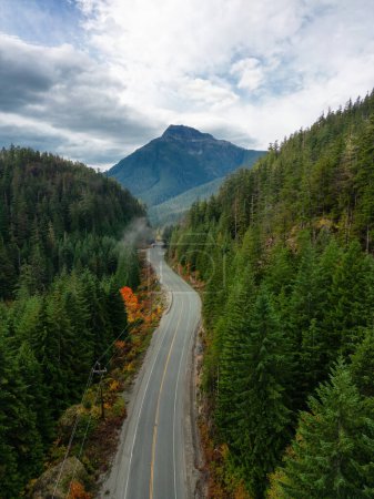 Foto de Scenic Highway by Trees with Mountains in Background. Cielo nublado de colores. Isla de Vancouver, Columbia Británica, Canadá. - Imagen libre de derechos