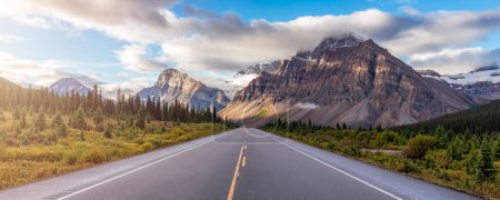 Foto de Scenic Road with green trees and Alpine Mountain Peaks in Canadian Nature Landscape. Alberta, Canadá. - Imagen libre de derechos
