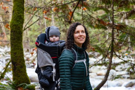 Photo for Mother Hiking with Baby in Backpack Carrier in Canadian Nature. Sunny Fall Day, Forest. Lynn Valley, North Vancouver, BC Canada. - Royalty Free Image