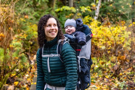 Photo for Mother Hiking with Baby in Backpack Carrier in Canadian Nature. Sunny Fall Day, Forest. Lynn Valley, North Vancouver, BC Canada. - Royalty Free Image