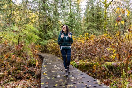 Téléchargez les photos : Mère randonnée avec bébé dans un sac à dos porteur dans la nature canadienne. Journée ensoleillée d'automne, Forest. Lynn Valley, North Vancouver, BC Canada. - en image libre de droit