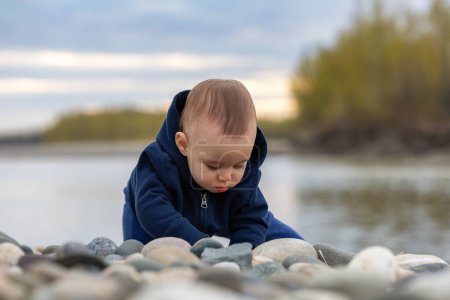 Bébé garçon caucasien jouant dehors avec des rochers par rivière. Chilliwack, Colombie-Britannique, Canada.