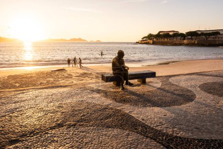 Foto de Hermosa vista al amanecer a la estatua del poeta sentado en el banco de la playa en Copacabana, Río de Janeiro, Brasil - Imagen libre de derechos