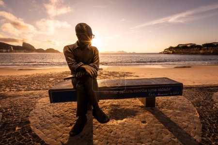 Téléchargez les photos : Belle vue du lever du soleil sur une statue de poète assise sur un banc de plage à Copacabana, Rio de Janeiro, Brésil - en image libre de droit
