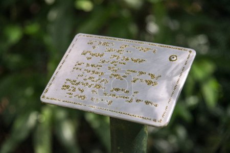 Cartel metálico con inscripciones en braille para visitantes ciegos en la selva verde Parque Tijuca, Río de Janeiro, Brasil
