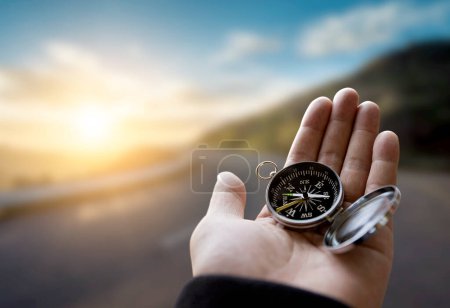 Photo for Traveler explorer man holding compass in a hand in mountains at sunrise, point of view. - Royalty Free Image