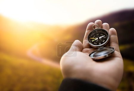 Photo for Traveler explorer man holding compass in a hand in mountains at sunrise, point of view. - Royalty Free Image