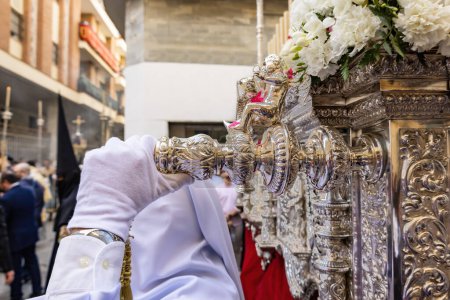 Photo for Detail of the hand with white glove of a costalero bearer carrying the paso (platform or Throne) of Holy week procession holding one of the silver varales, stringers that are placed horizontally - Royalty Free Image