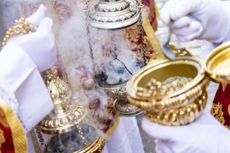 Téléchargez les photos : Detail of the hand of an altar boy or acolyte in a Holy Week procession filling one of the censers with incense - en image libre de droit