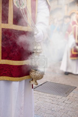 Téléchargez les photos : Censeur secoué par un enfant de chœur ou un acolyte lors de la procession de la semaine sainte pour produire de la fumée et des parfums d'encens - en image libre de droit
