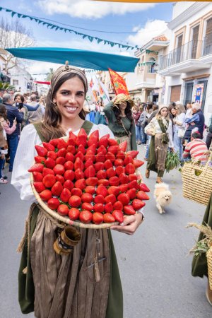 Photo for Huelva,Spain-March 18, 2023:A huge plate with big strawberries, variety Freson de Palos, in the hand of a young woman parading in the Medieval Discovery Fair in Palos de la Frontera, Huelva, Andalusia - Royalty Free Image