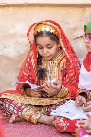Foto de Nizwa, Oman, 2nd December 2022: omani girls reciting a Holy Book - Imagen libre de derechos