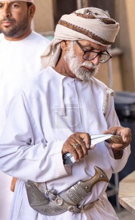 Téléchargez les photos : Nizwa, Oman, 2 décembre 2022 : homme omani en tenue traditionnelle au marché des armes - en image libre de droit