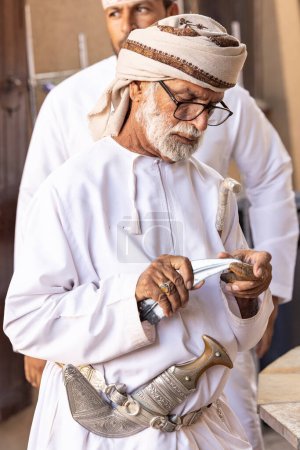 Foto de Nizwa, Oman, 2nd December 2022: omani man in traditional outfit at the weapon market - Imagen libre de derechos