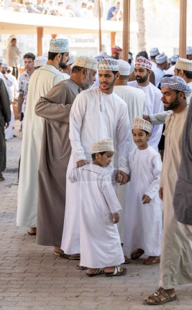 Téléchargez les photos : Nizwa, Oman, 2 décembre 2022 : Homme omanais avec ses fils dans un marché traditionnel - en image libre de droit