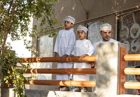 Photo for Nizwa, Oman, 2nd December 2022: Omani man with his sons in a traditional market - Royalty Free Image