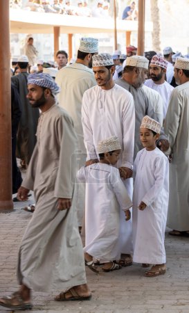 Téléchargez les photos : Nizwa, Oman, 2 décembre 2022 : Homme omanais avec ses fils dans un marché traditionnel occupé - en image libre de droit