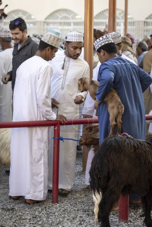 Foto de Nizwa, Oman, 2nd December 2022: Omani men at the market buysing and selling goats - Imagen libre de derechos