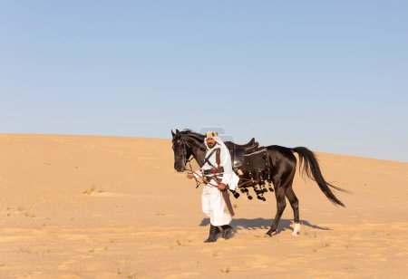 Photo for Saudi arabian man riding on his black stallion in a desert - Royalty Free Image