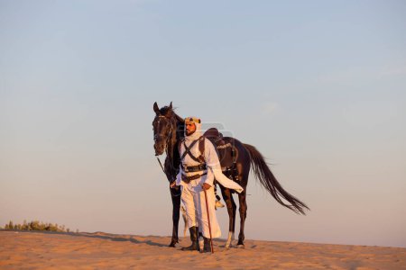 Foto de Hombre saudí en un desierto con su caballo negro - Imagen libre de derechos