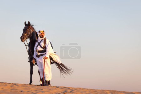 Photo for Saudi man in a desert with his black horse - Royalty Free Image