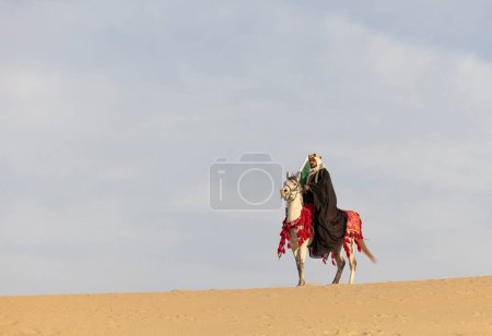 Téléchargez les photos : Homme en costume traditionnel avec son cheval dans un désert - en image libre de droit