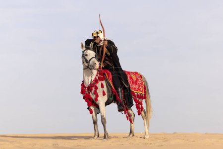 Man in traditional clothing with his horse in a desert