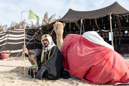 Photo for Bedouin man with his falcon and camel resting in front of his tent - Royalty Free Image