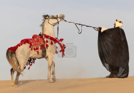 Photo for Saudi man in traditional clothing with his white stallion - Royalty Free Image