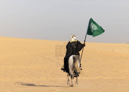 Téléchargez les photos : Homme saoudien en vêtements traditionnels avec son étalon blanc - en image libre de droit