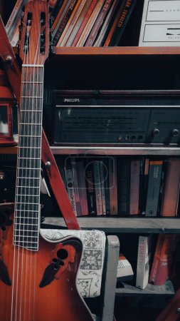 Foto de Libros en los estantes, una vieja radio Philips y una guitarra clásica de pie delante de ellos. 10.24.2022 Estambul, Turquía - Imagen libre de derechos