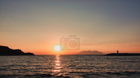 Téléchargez les photos : Vue sur le port maritime, le phare, les montagnes et l'île opposée de Samothrace à Gkeada, île d'Imbros au coucher du soleil - en image libre de droit